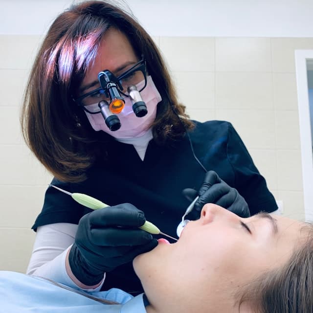 Chirurgienne-dentiste au travail avec loupes binoculaires
